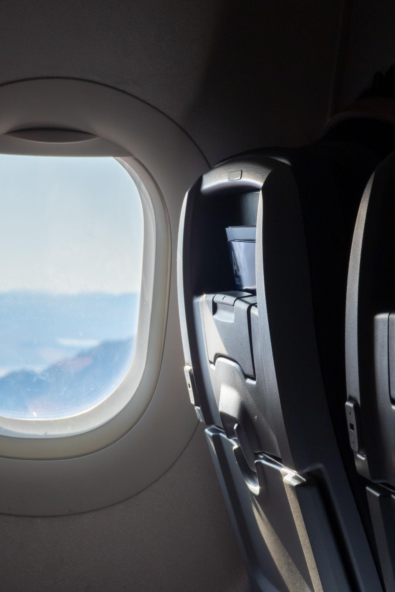 A RAW photo file showing an airplane window and seat, edited to change its aspect ratio.