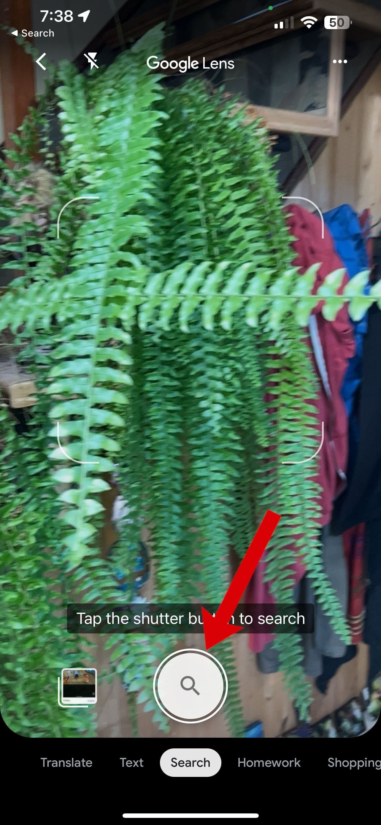 Ένα στιγμιότυπο οθόνης του Google Lens για iOS με ένα βέλος που δείχνει το κουμπί κλείστρου.