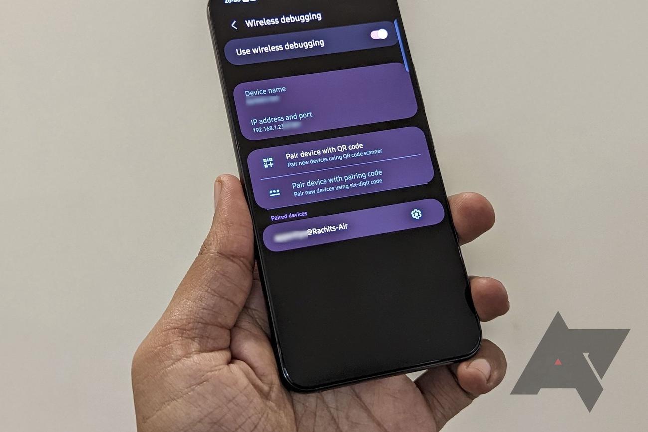 A person holds an Android phone with the wireless debugging menu opened.