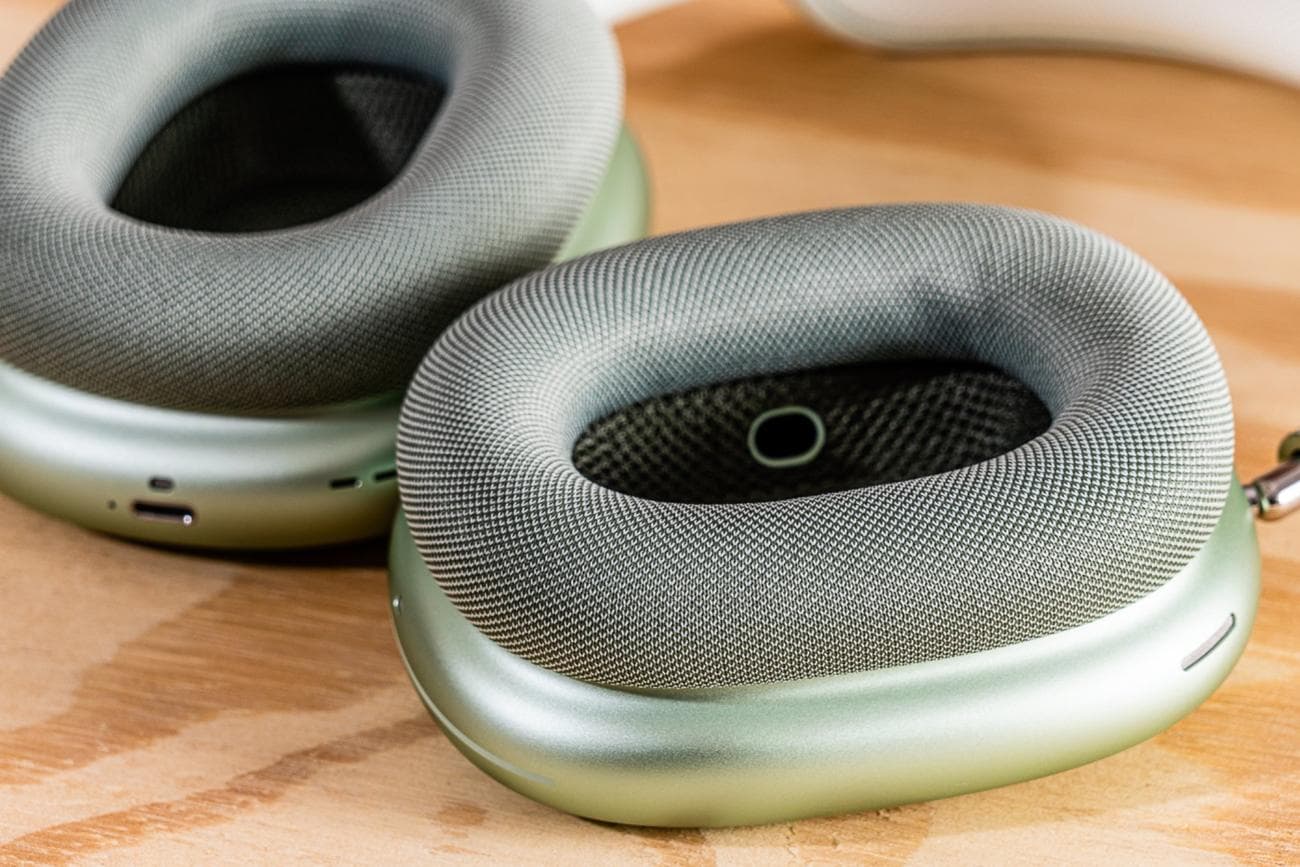 The insides of the ear cups on a pair of Apple AirPods Max headphones on a wooden surface.