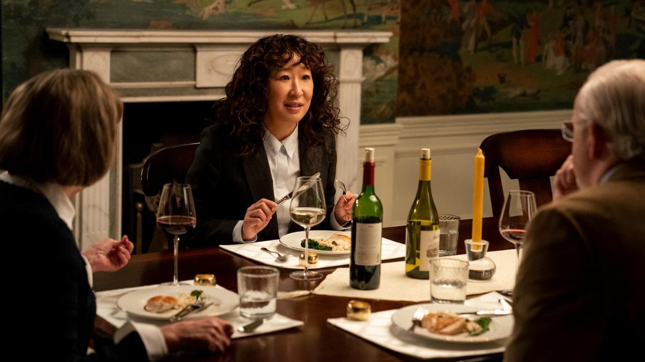 A woman sits at a dinner table with two other people.