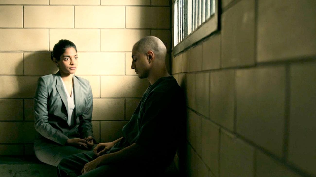 A woman in a suit suits in a prison consultation room with a man.