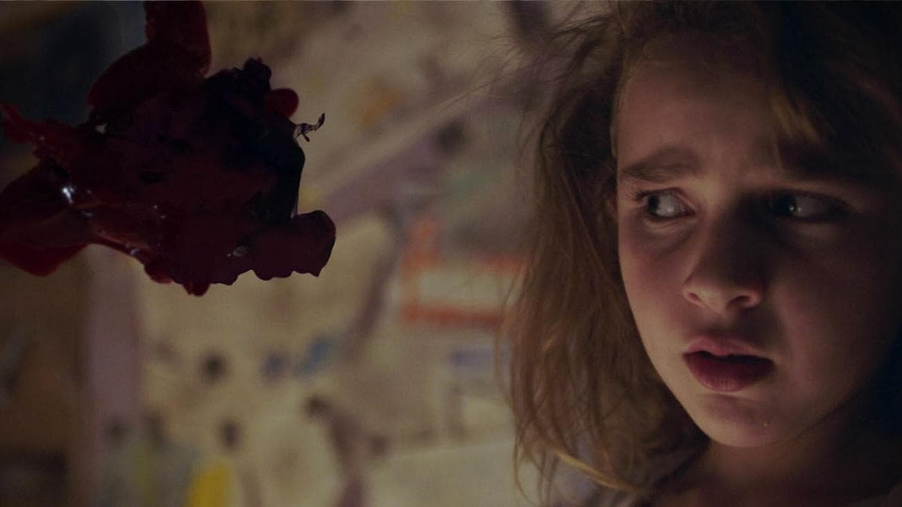 A girl looks to her right with a terrified expression.