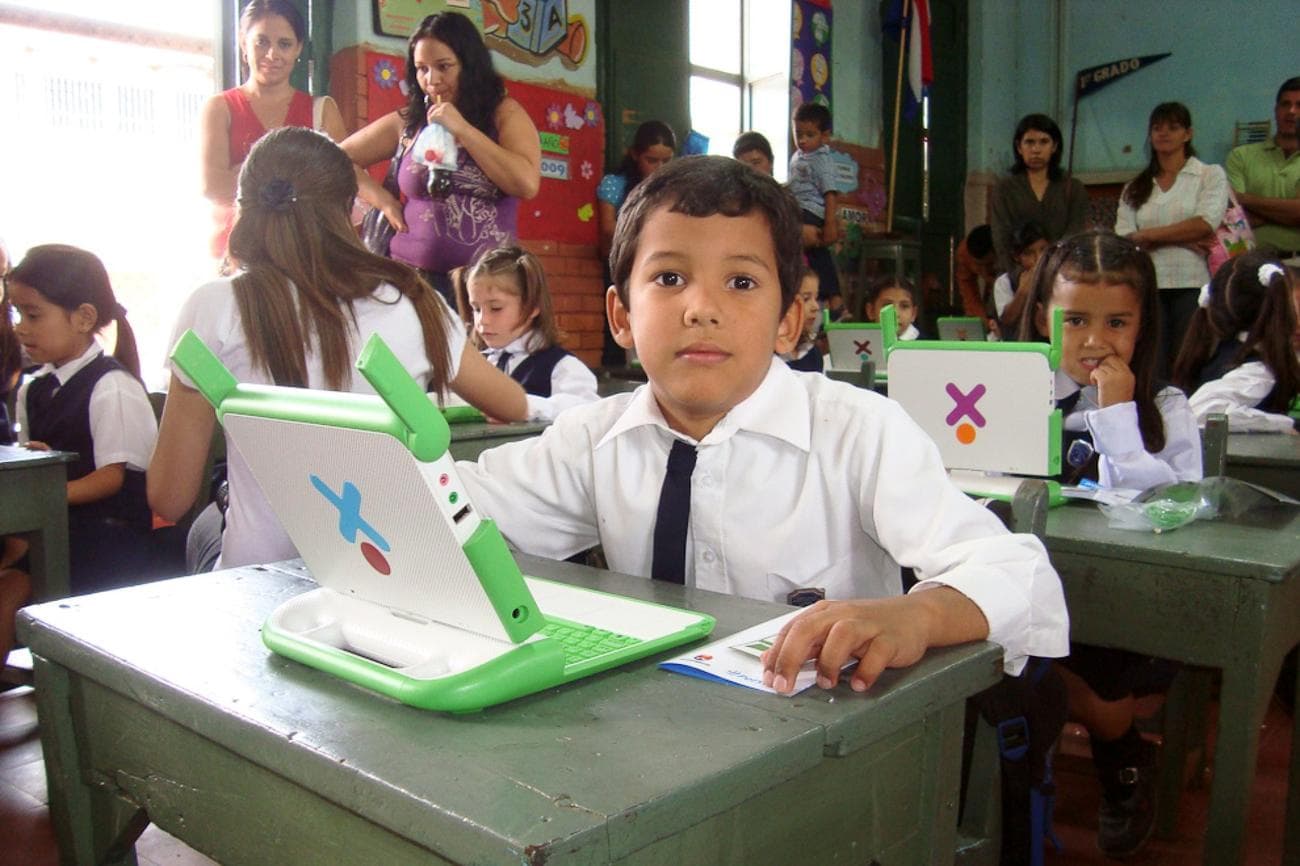 Children sitting in a classroom, using XO Laptops.