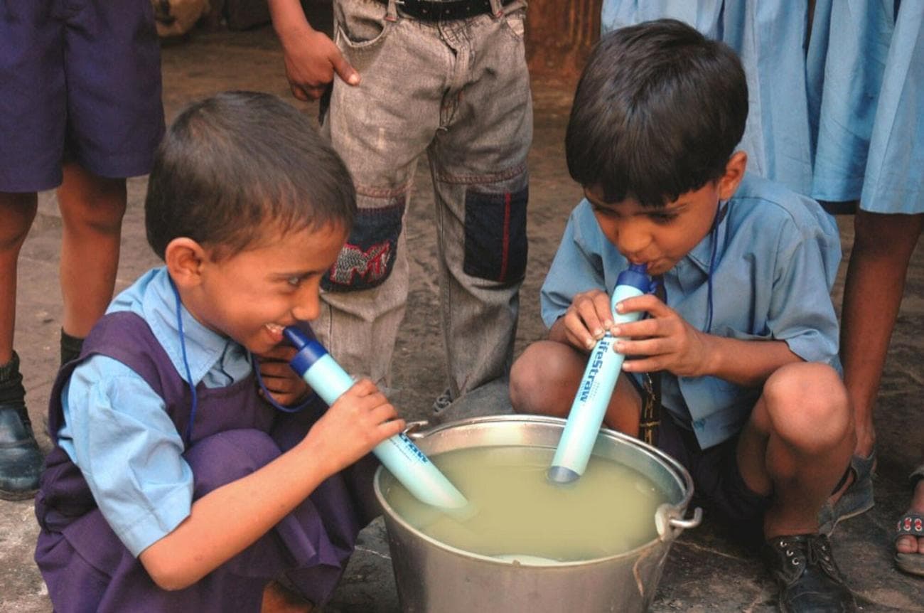 Two young boys using LifeStraws.