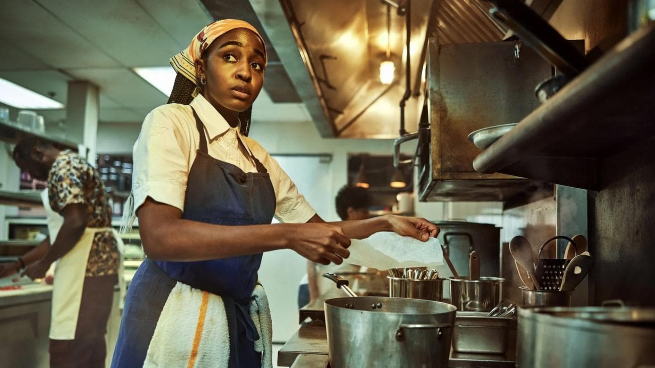 A chef tends pots in a commercial kitchen.