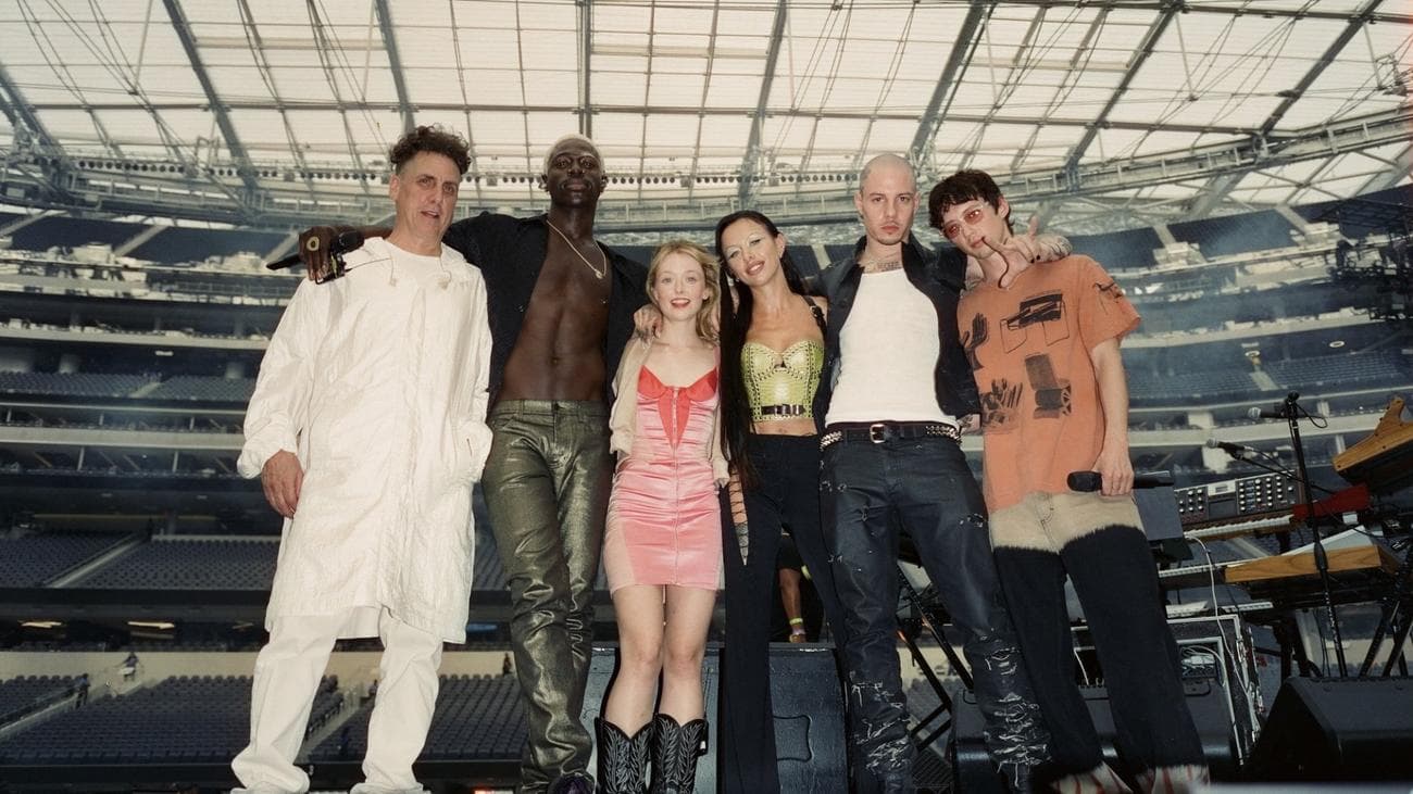 Μια ομάδα ποπ σταρ και παραγωγοί στη σκηνή σε ένα τεράστιο στάδιο.