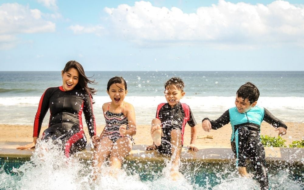 A woman and children splashing their feet in water with the best sunscreen