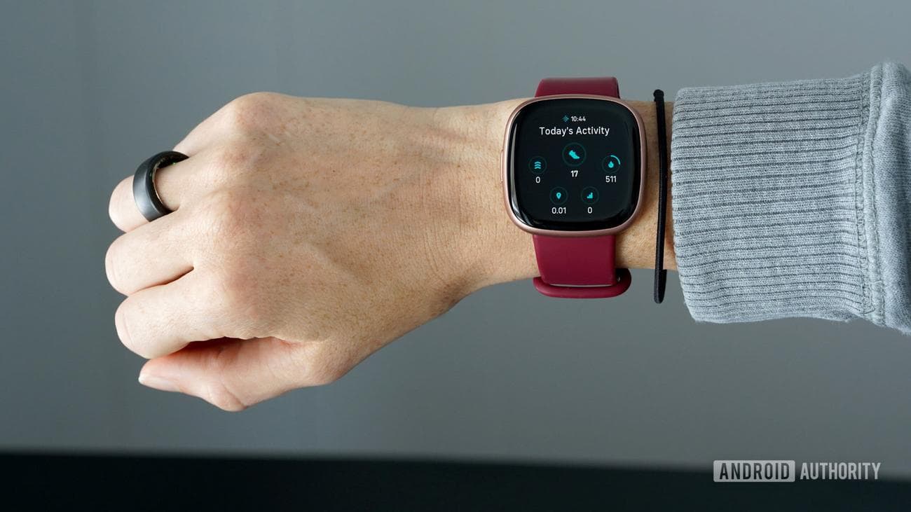 Ένας καρπός φοράει ένα Fitbit Versa 4 με ένα δαχτυλίδι Oura 3 στο ίδιο χέρι.