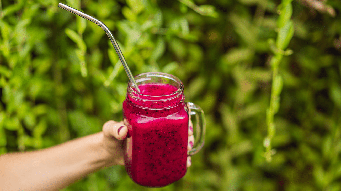 A woman holds a red smoothie in a glass with a handle on it and a stainless steel straw sticking out. A group of ‘forever chemicals’ commonly called PFAS were not detected on the stainless steel straws in this study, but were on 18 out of 20 brands of paper straws.