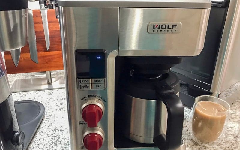 Wolf Gourmet best splurge drip coffee maker in chrome with red knobs on a crowded kitchen counter
