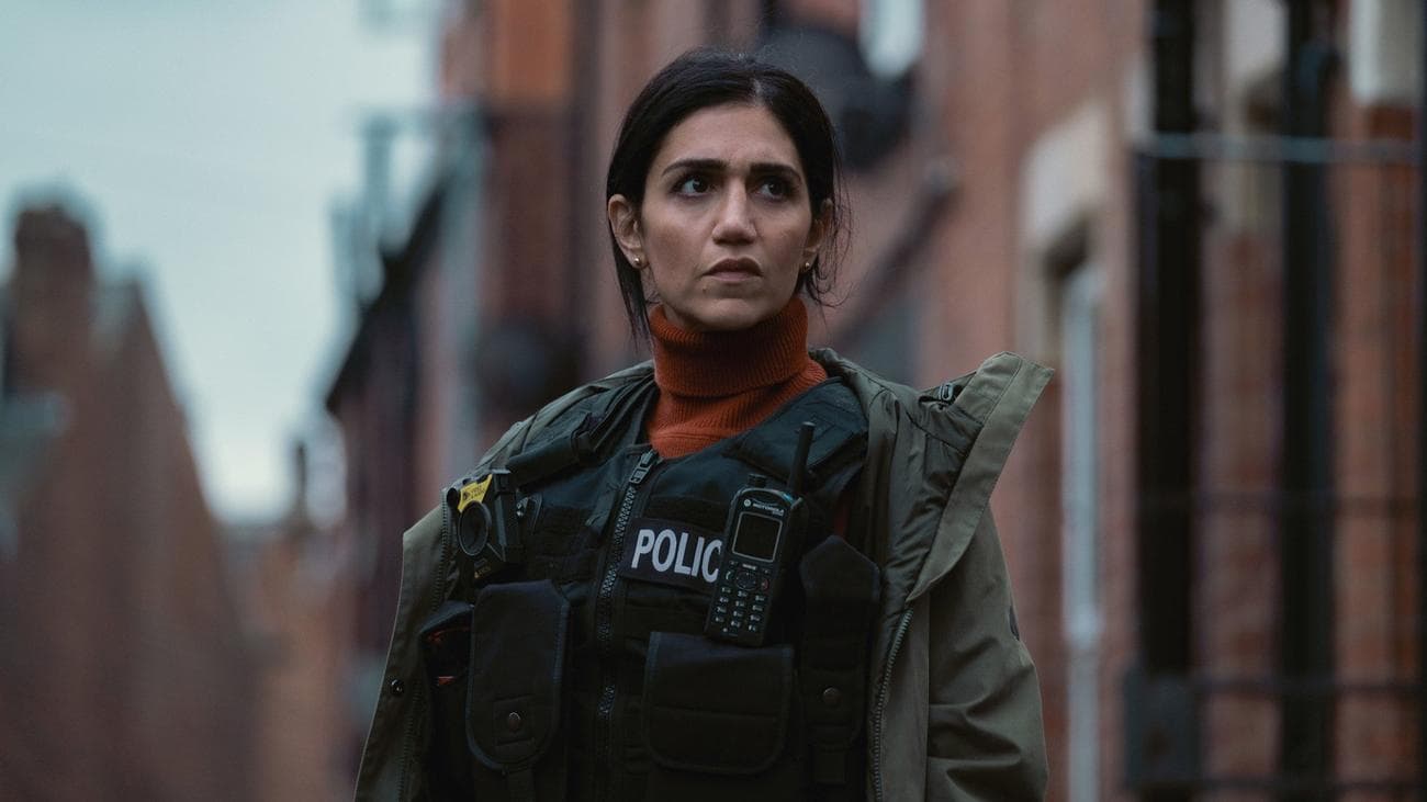 Leila Farzad stands in the street wearing a bulletproof vest and a coat in the show "Better"