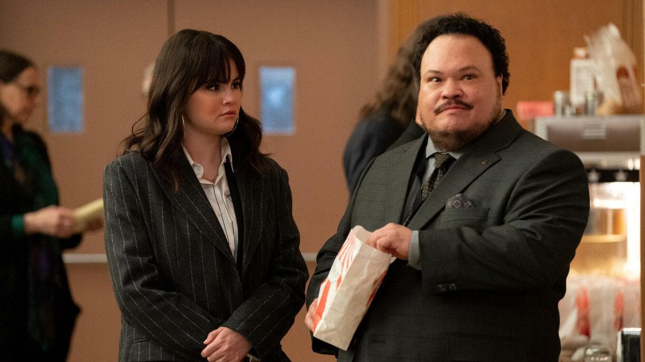 A woman and man wearing black suits eat popcorn at a funeral service. 
