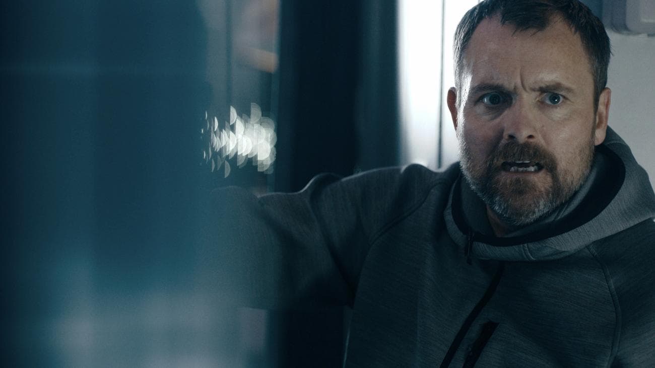 Ένας άντρας σε ένα διάδρομο αεροπλάνου φαίνεται ανήσυχος.