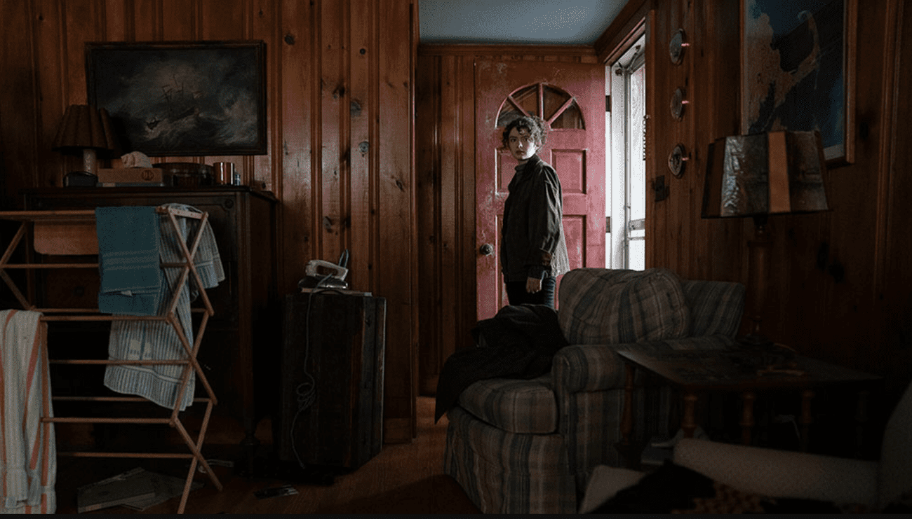 A woman stands in the doorway of a house.