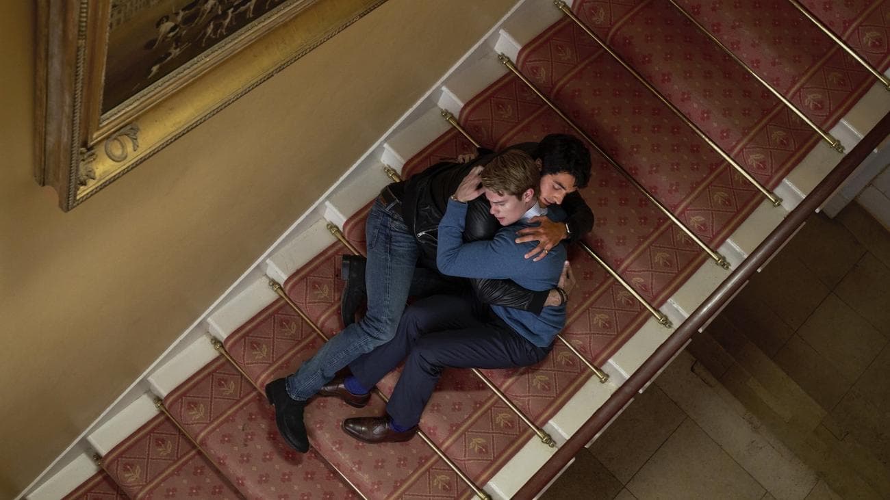 Δύο άντρες αγκαλιάζονται ξαπλωμένοι σε μια σκάλα.