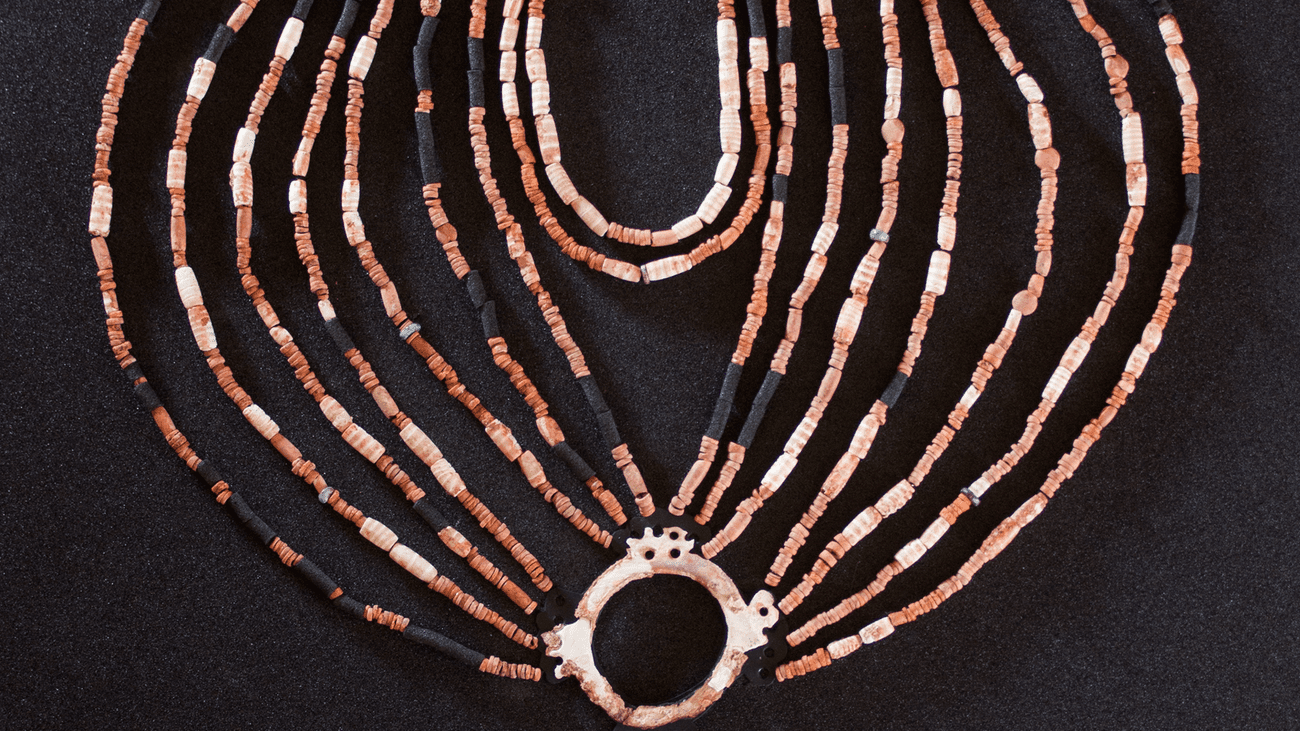 The physical reconstruction of the necklace found in the Neolithic village of Ba’ja in Jordan. It has about 16 strands of beads that meet together in a circle with a gemstone in it and three other strands on top.