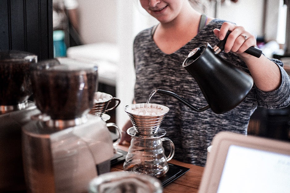 Woman pouring water from an electric kettle into a pour over coffee maker