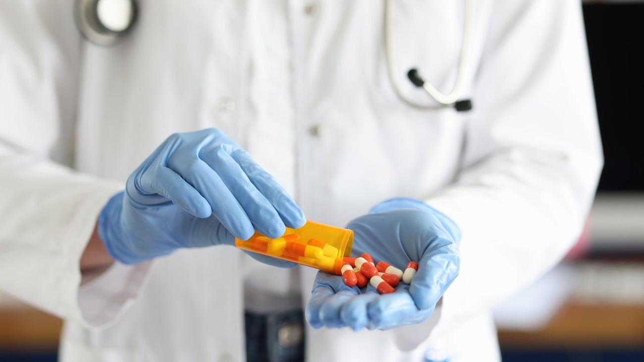 Doctor pouring pills in hand from bottle.