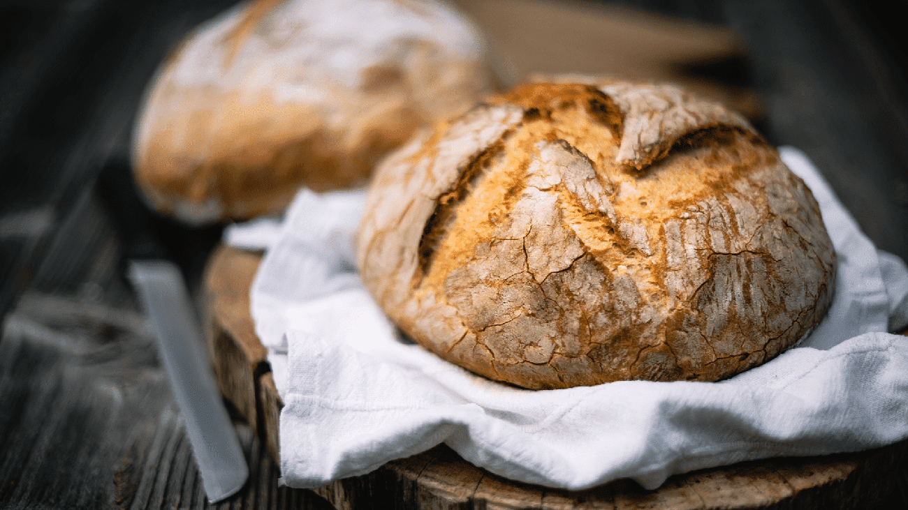 Two loaves of rustic sourdough bread on a wooden counter.