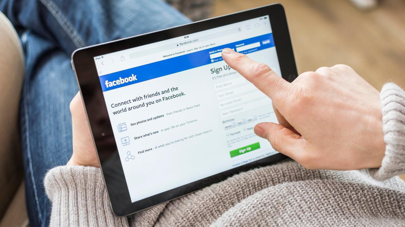 Woman in sweater logging into Facebook on a tablet