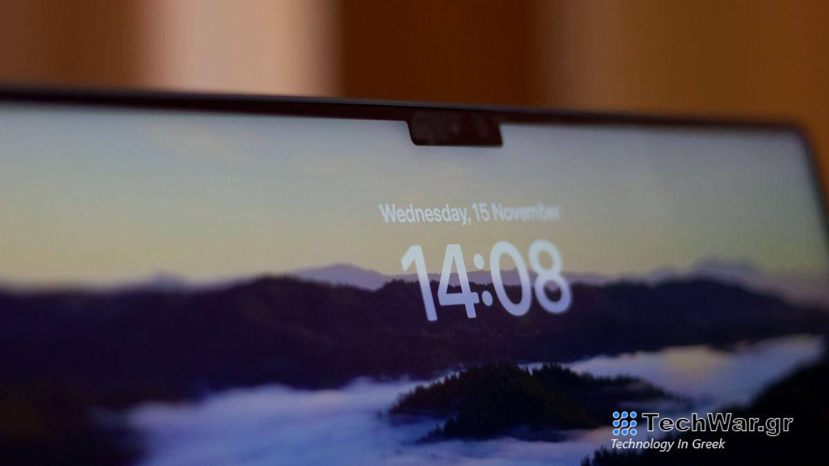 A MacBook display showing the time, 14:08, on a mountain background