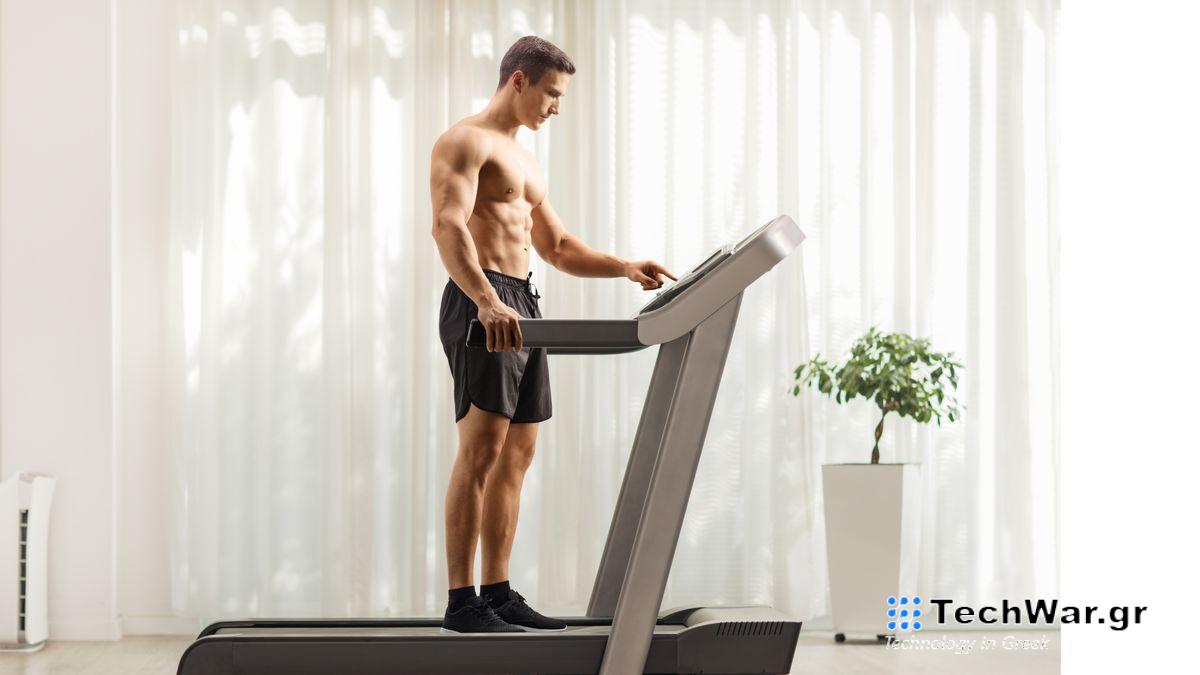 Muscular man standing on treadmill during home workout