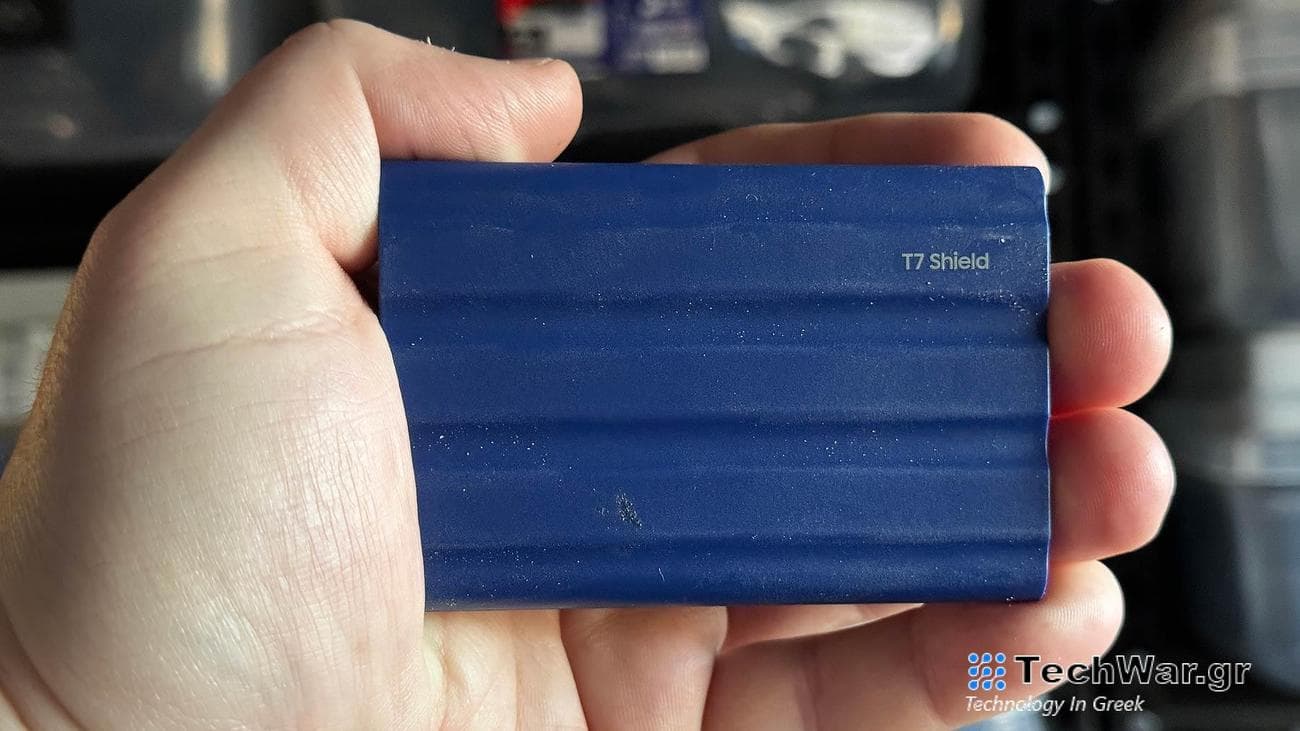 A hand holding a blue samsung T7 shield portable SSD