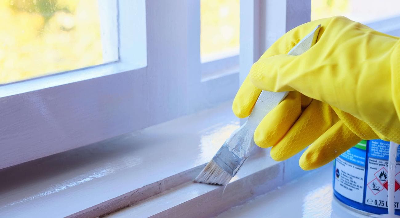 Άτομο που ζωγραφίζει ένα περβάζι με μια γυαλιστερή λευκή μπογιά