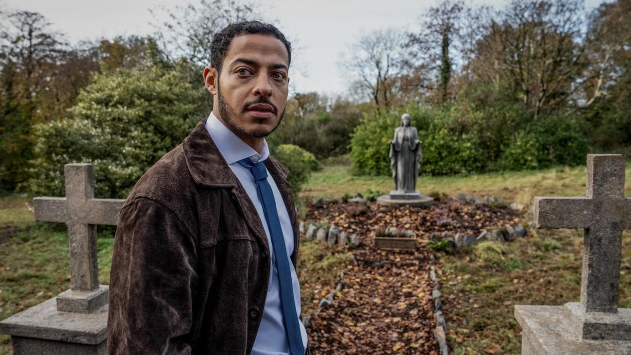 Ο Ντάριλ ΜακΚόρμακ στέκεται σε ένα νεκροταφείο και ερευνά κάτι στην τηλεοπτική εκπομπή "Η Γυναίκα στον Τοίχο"