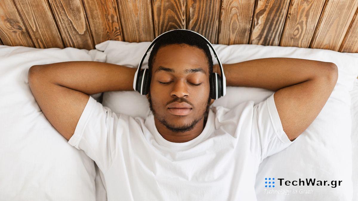 A man lying in bed listening to white noise through headphones