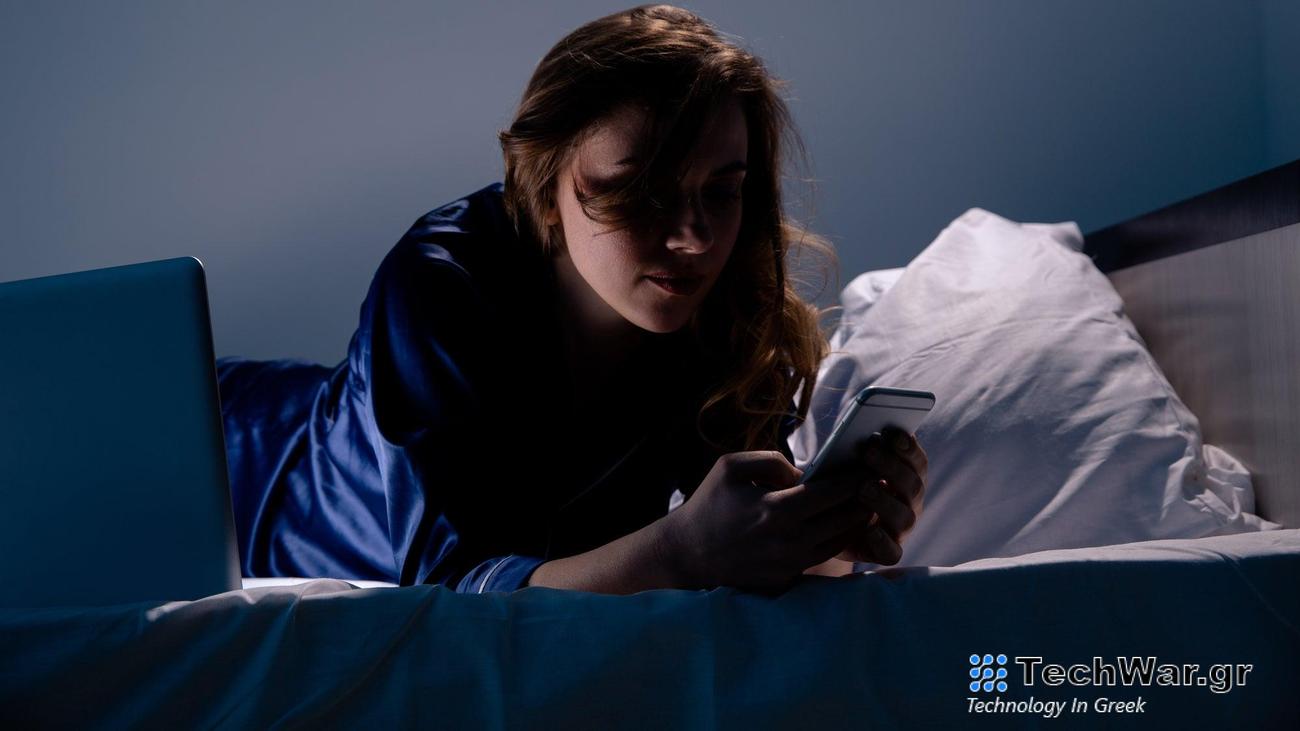 Woman on phone in bed in darkened room with face obscured