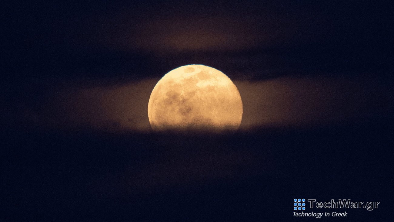 The full moon rises, with clouds below and behind it.