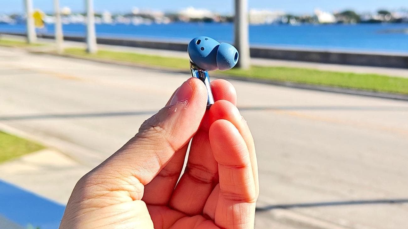 Το OnePlus Buds 3 δείχνει κοντινό πλάνο ακουστικών που κρατούνται ανάμεσα στα άκρα των δακτύλων