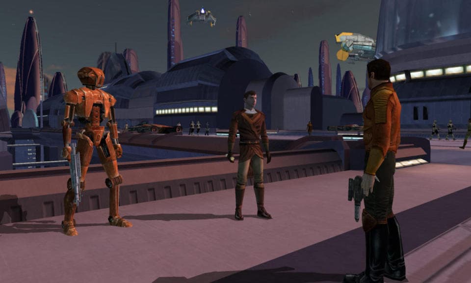Ακόμα από το Star Wars: The Knights of the Old Republic.  Δύο άτομα και ένα droid στέκονται έξω σε μια γέφυρα σε ένα πολύ περιβάλλον Star Wars-y.  Κτίρια, πλοία, πύργοι.