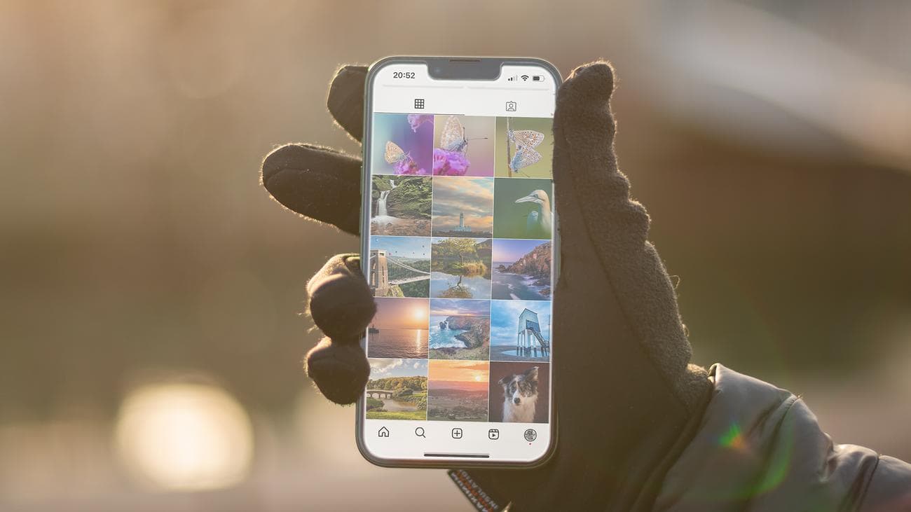 Ένα χέρι που κρατά ένα iPhone 13 που εμφανίζει μια ροή Instagram