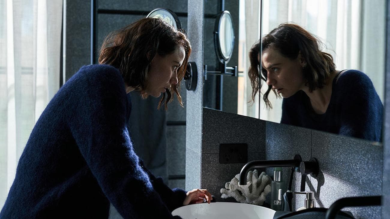 Μια γυναίκα κοιτάζει τον εαυτό της στον καθρέφτη.