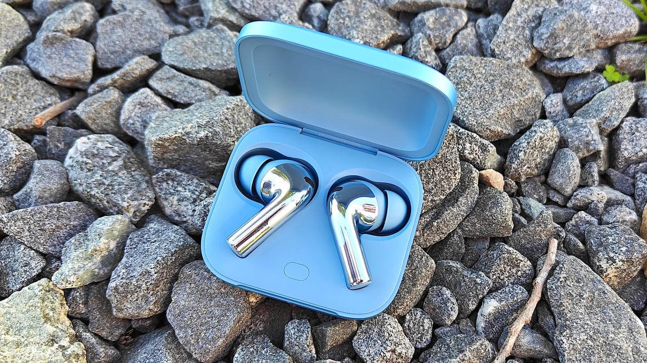 Το OnePlus Buds 3 σε θήκη φόρτισης τοποθετείται σε μερικές πέτρες