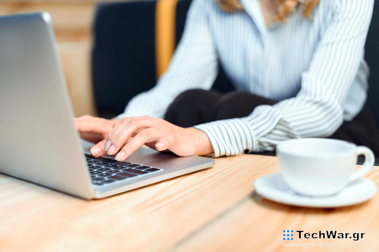 hands working on a laptop with a coffee