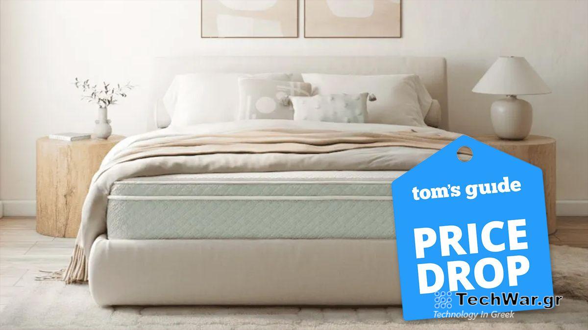 Allswell Home Organic Mattress on a beige bedframe in a neutral coloured bedroom, with a blue price drop badge overlaid on the image