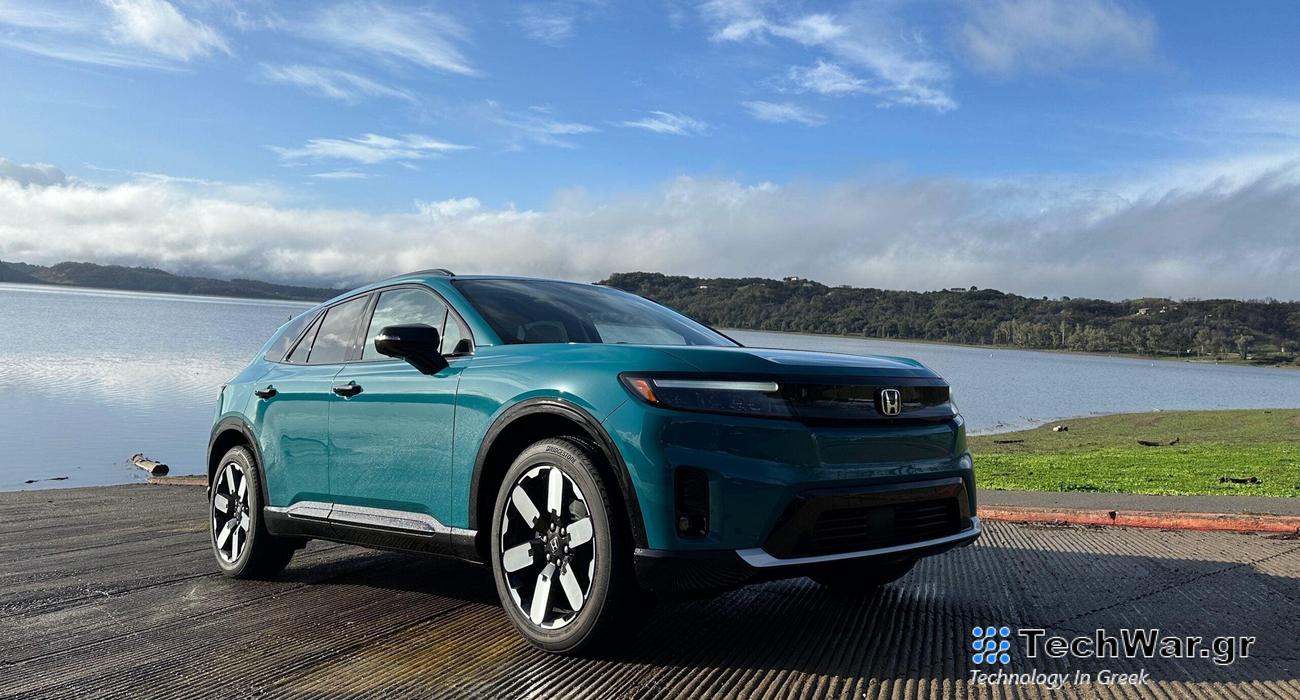 a greenish-blue SUV sits in front of a lake