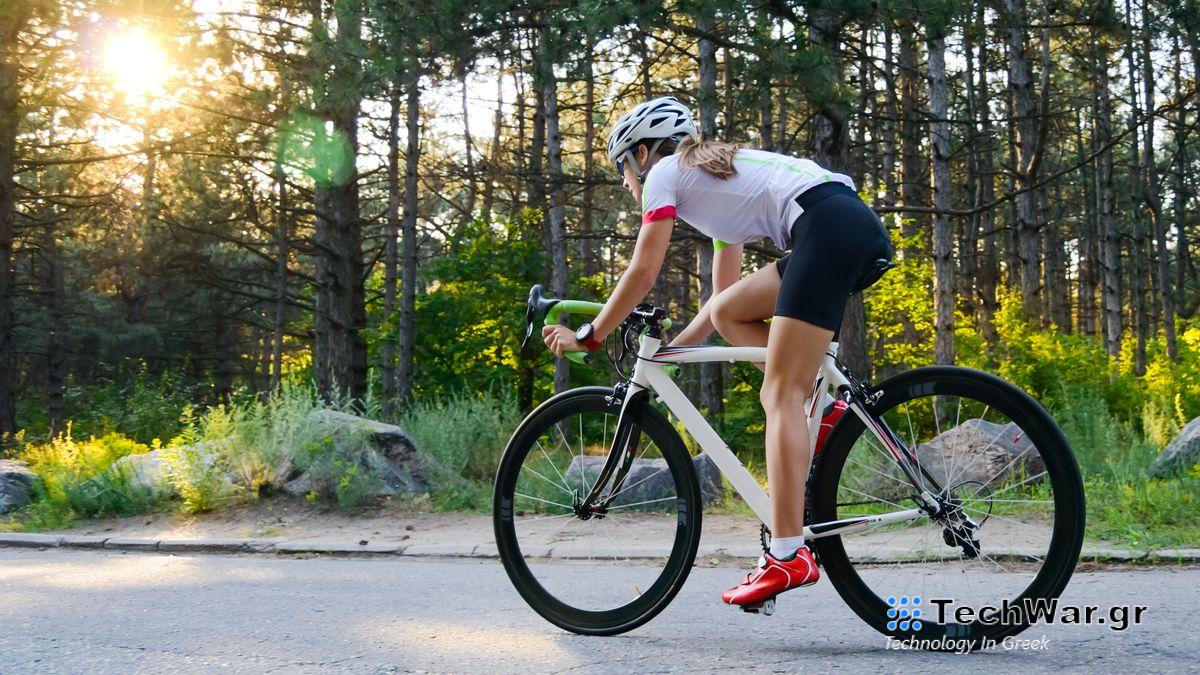 a woman riding a bike on a road surrounded by trees
