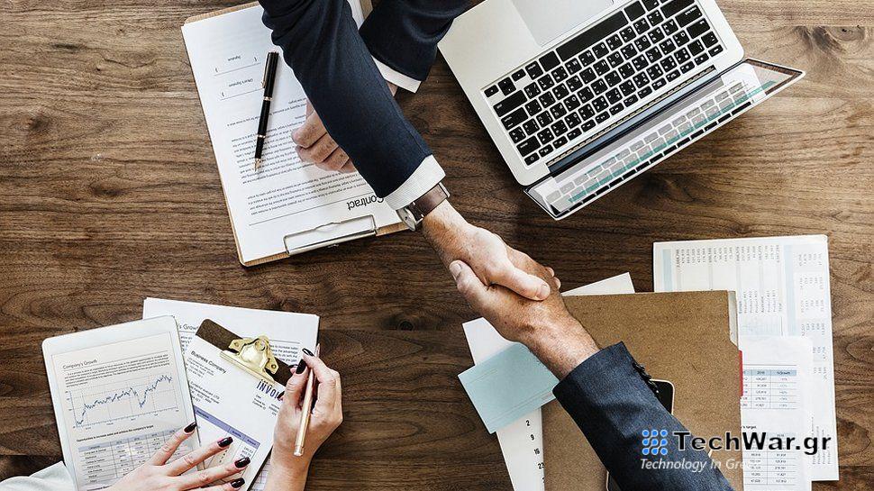 Two people shaking hands across a corporate desk